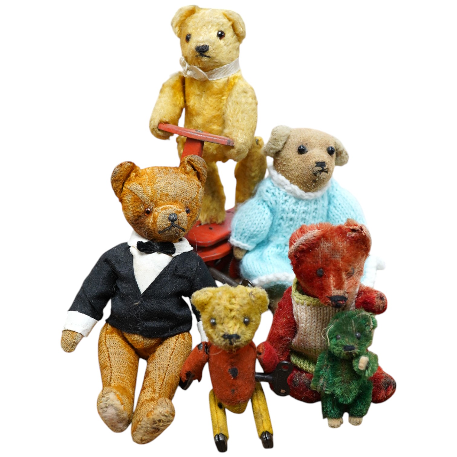 A mechanical bear on a bike in good working condition, a red Schuco bear, faded condition, c.1920, 13cm, a tumbling Schuco bear, working, 10cm, c.1920, a green Schuco bear missing one ear, c.1920, 7cm. high, together wit